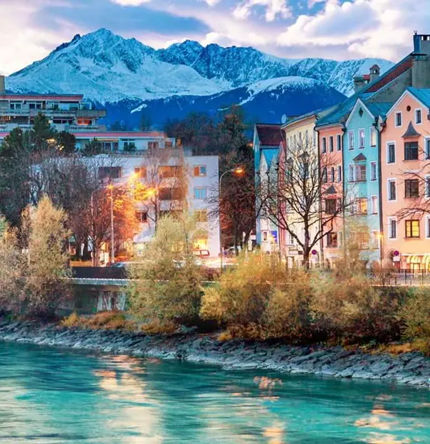 Buildings on the waterfront in Innsbruck, Austria with snowy mountains in the background