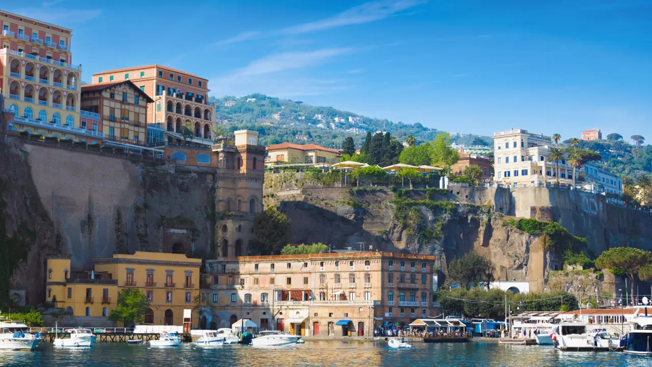 A sunny day in Sorrento, Italy, with multicoloured luxury hotels on the cliffs above a peaceful marina