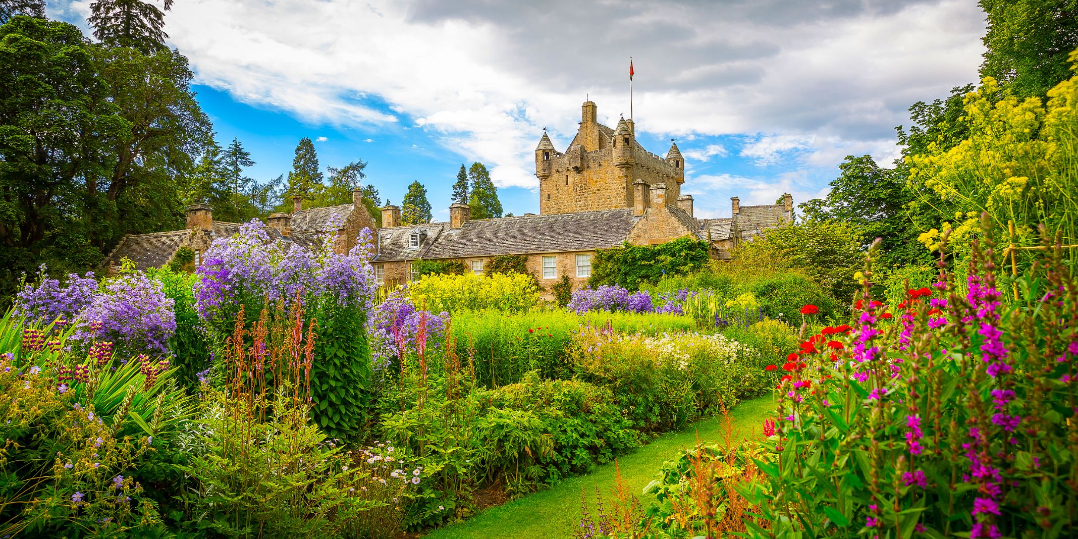 View of Cawdor Castle from the gardens, with colourful flowers and greenery in the forefront
