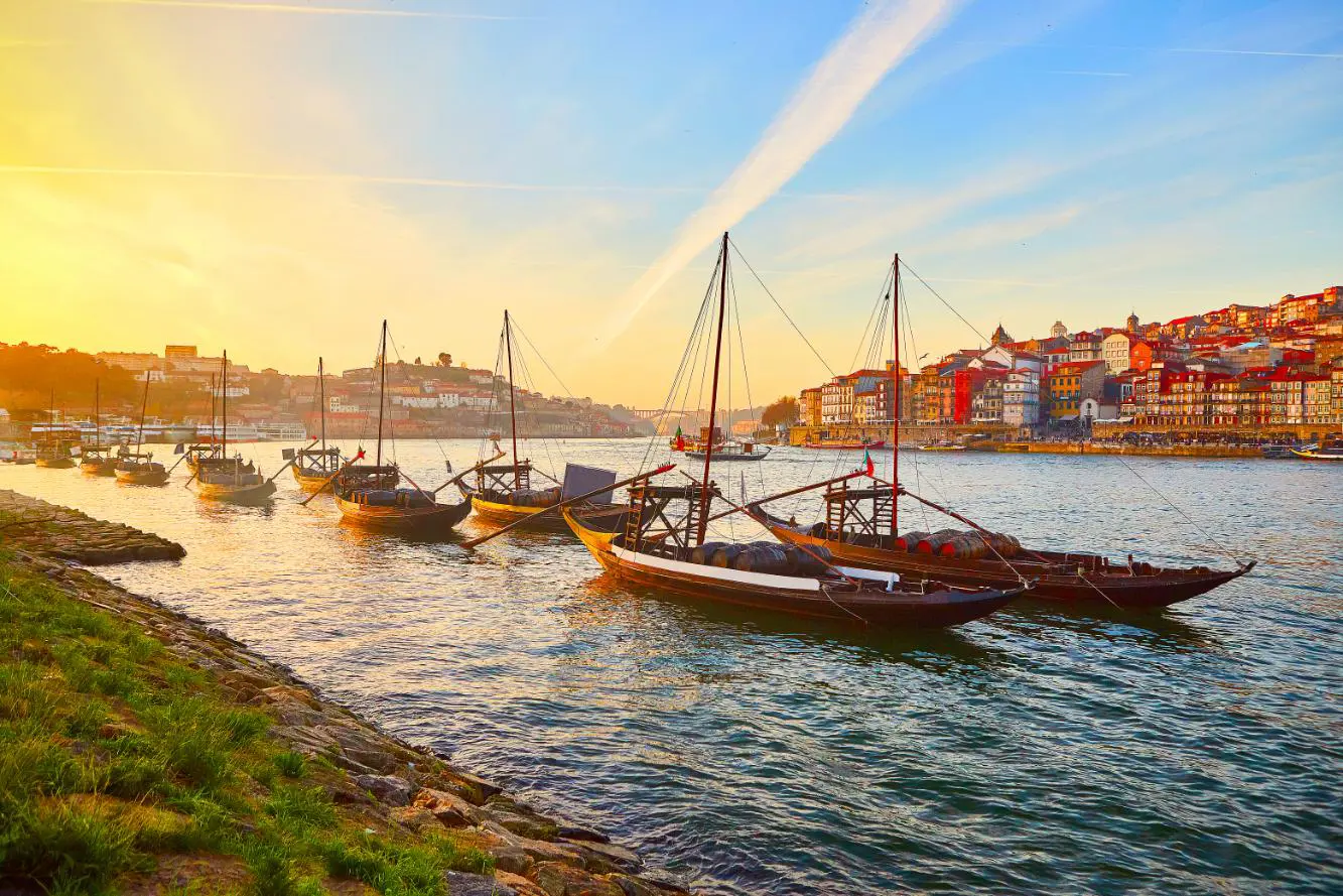 Traditional Wooden Boats, Called Barcos Rabelos Transporting Wine Barrels On The River Douro