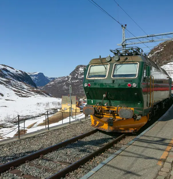 The Flåm Railway travelling through Norway's snowy mountains