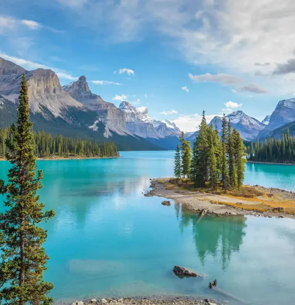 Scenic view of Spirit Island on Maligne Lake in Jasper National Park, Canada, surrounded by turquoise water, pine trees, and snow-capped mountains