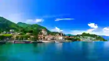 Lake Maggiore in Italy, with an Italian town on the shore beneath a bright, partly cloudy sky