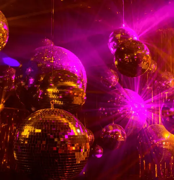 Silver disco balls hanging from the ceiling, catching light and casting shimmering patterns across a dark room