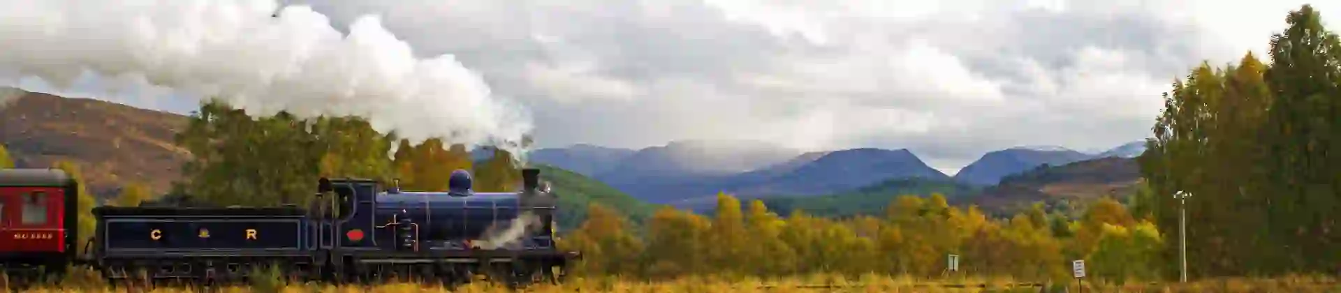 Steam train approaches Kinchurdy Bridge against Cairngorms