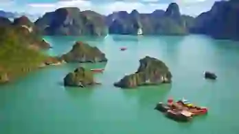 Traditional wooden boats sailing among limestone islands in Ha Long Bay, Vietnam