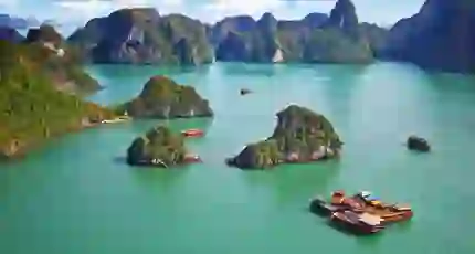 Traditional wooden boats sailing among limestone islands in Ha Long Bay, Vietnam