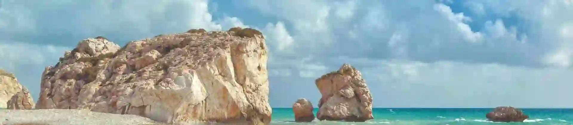 A cloudy day with waves crashing on a pebbled beach near Aphrodite’s Rock in Cyprus