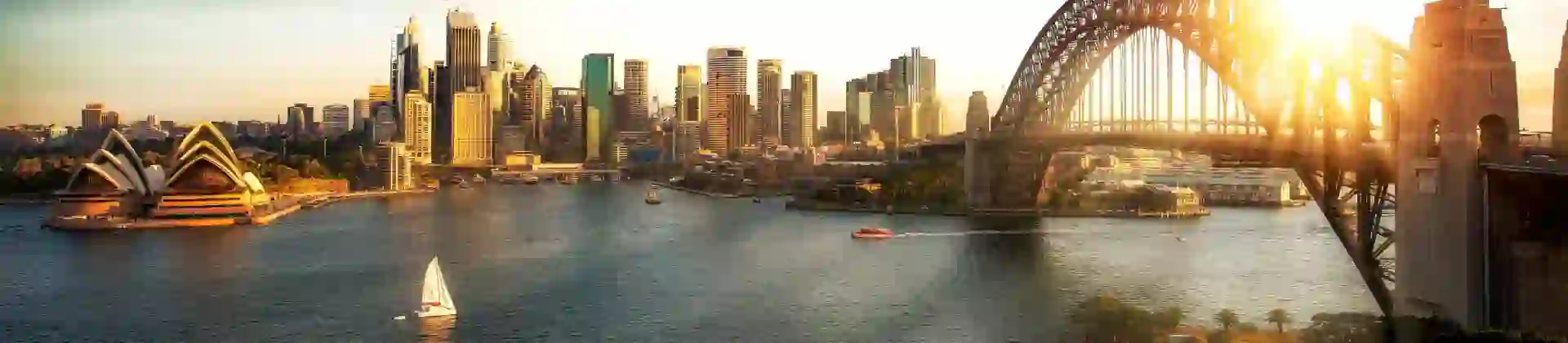 The Sydney Opera House beside Sydney Harbour with the city skyline in the background.