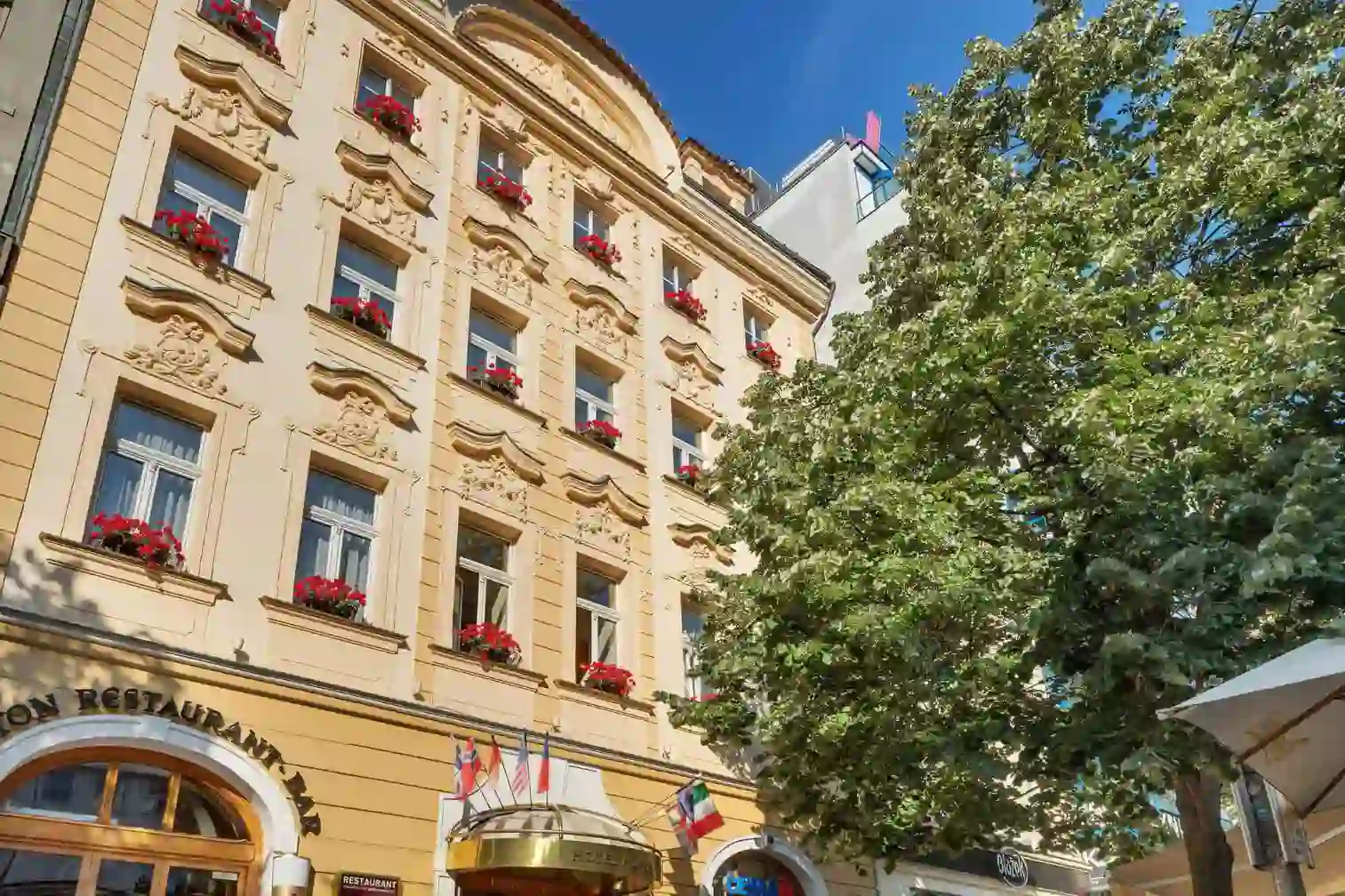 Façade of Hotel Adria in Prague with flower-adorned windows and ornate details