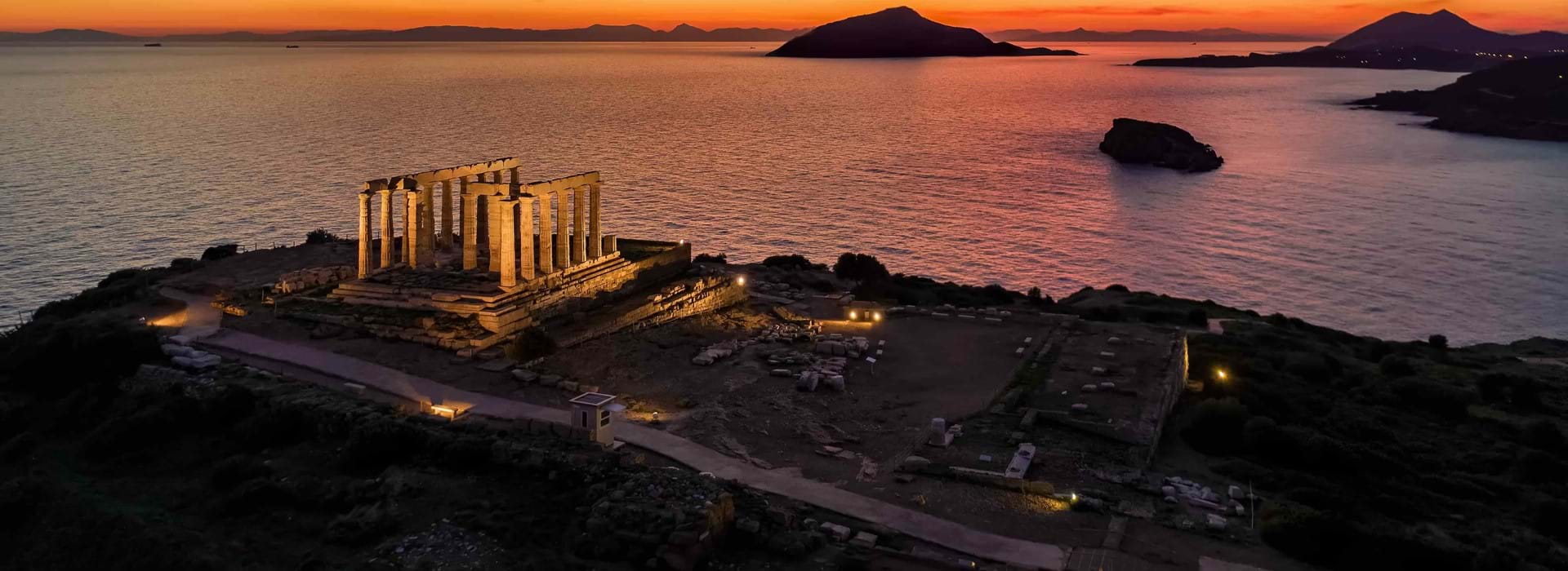 High angle view of some ruins on the land's edge, with the view of the sea and orange sunset 