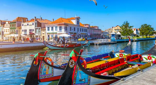 Brightly painted gondola-style boats moored along a canal lined with colourful buildings in Aveiro, Portugal