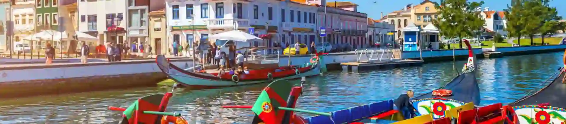 Brightly painted gondola-style boats moored along a canal lined with colourful buildings in Aveiro, Portugal