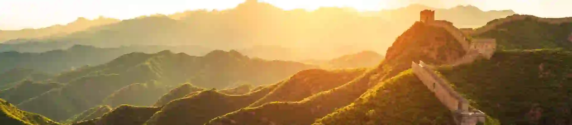 The Great Wall winding over green mountains at sunset, Beijing, China