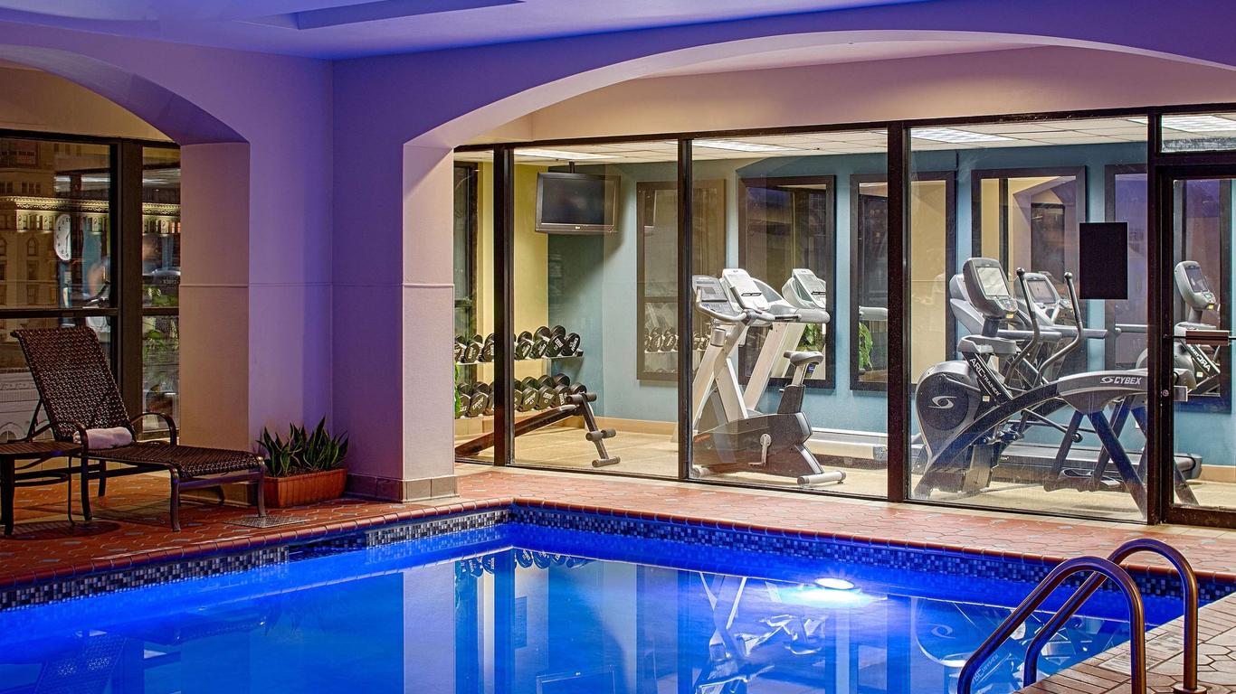 Indoor pool area at the Wyndham French Quarter, featuring a vibrant blue swimming pool adjacent to a fitness centre with exercise equipment visible through large glass windows