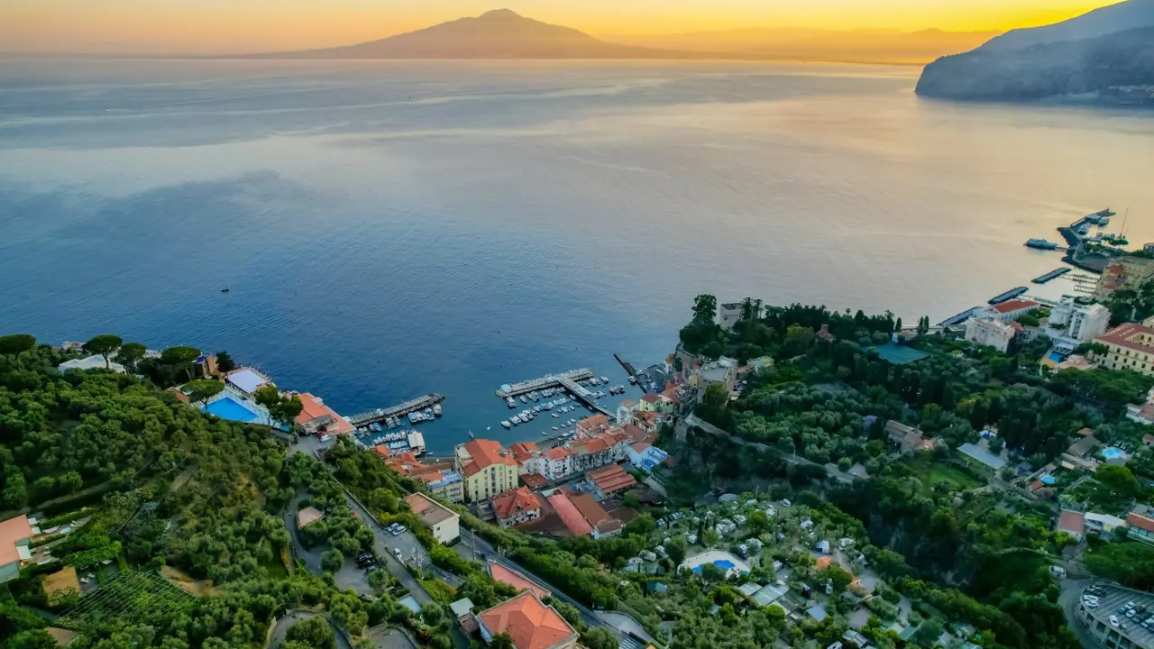 An aerial view of Sorrento on the Amalfi Coast, Italy at sunrise with Naples and Mount Vesuvius in the background