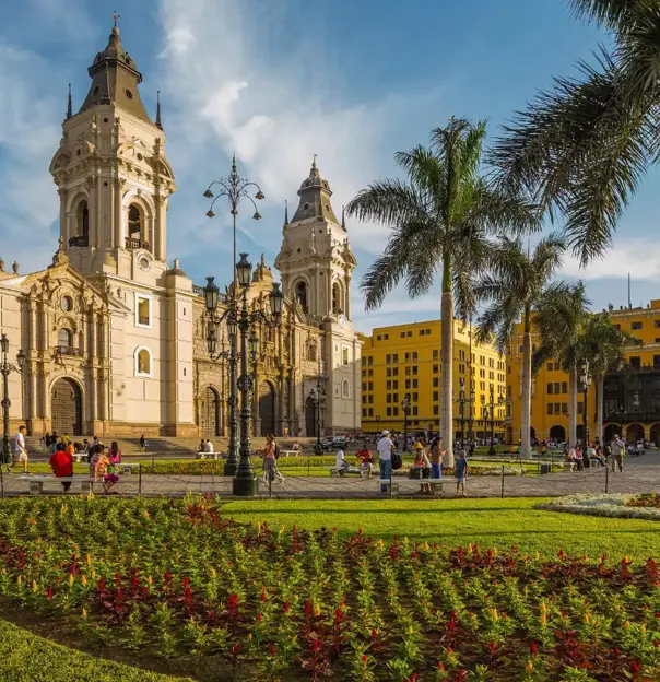 A view of the Cathedral of Lima in the Main Square of Lima, Peru, featuring colonial architecture, palm trees, and a sunny sky in the background