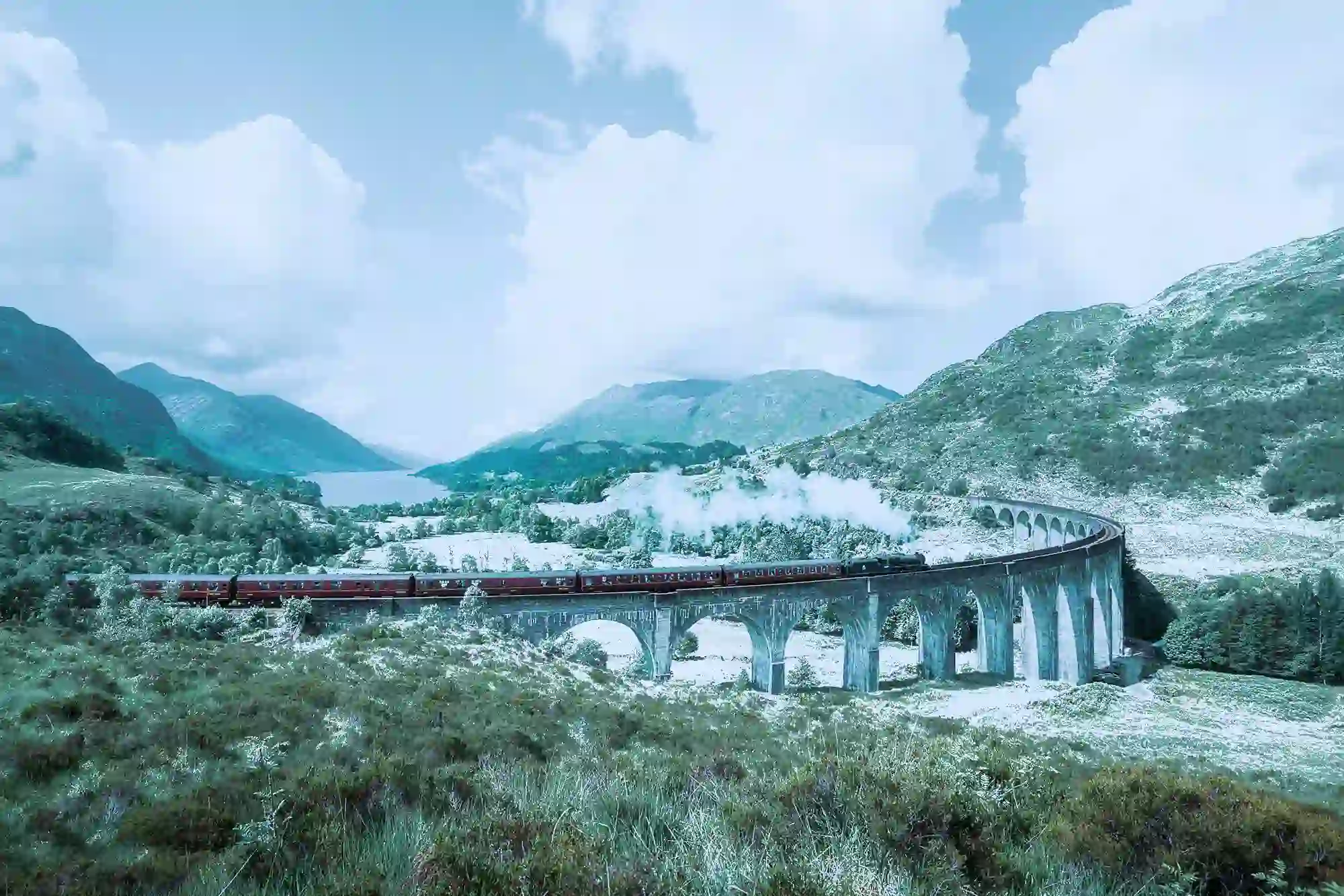 Train going along a viaduct in the snow in the Highlands