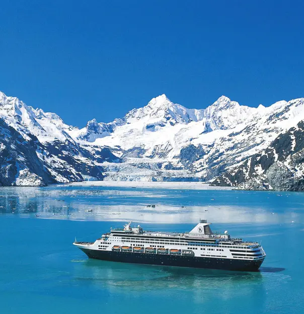 The MS Koningsdam cruise ship sailing through Glacier Bay, surrounded by calm icy waters and dramatic snow-capped mountains