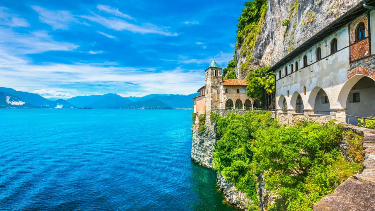 A scenic view of Lake Maggiore in Italy, with charming buildings along the water’s edge and mountains rising in the distance