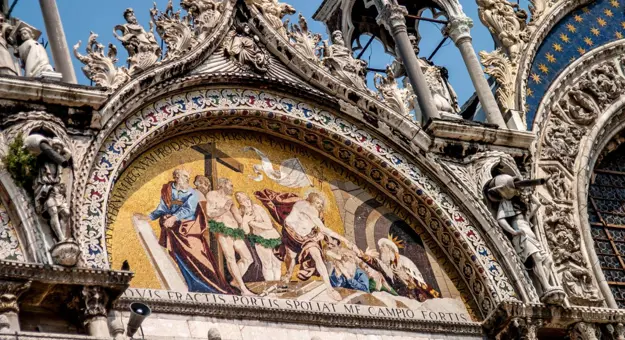 Intricate mosaics with vibrant gold backgrounds and detailed figures above the entrance of Saint Mark's Basilica in Venice, Italy