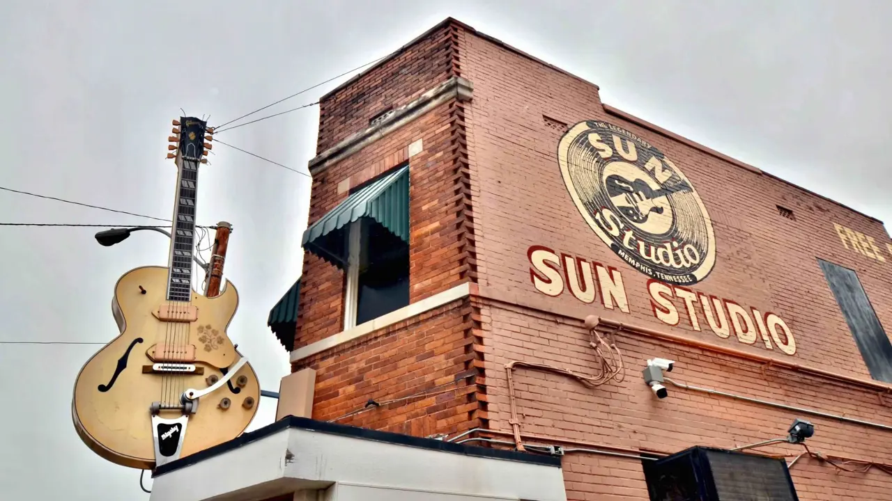 Sun Studio building with orange brick exterior, a large guitar-shaped sign outside, and the words “Sun Studio” painted in yellow on the side of the building