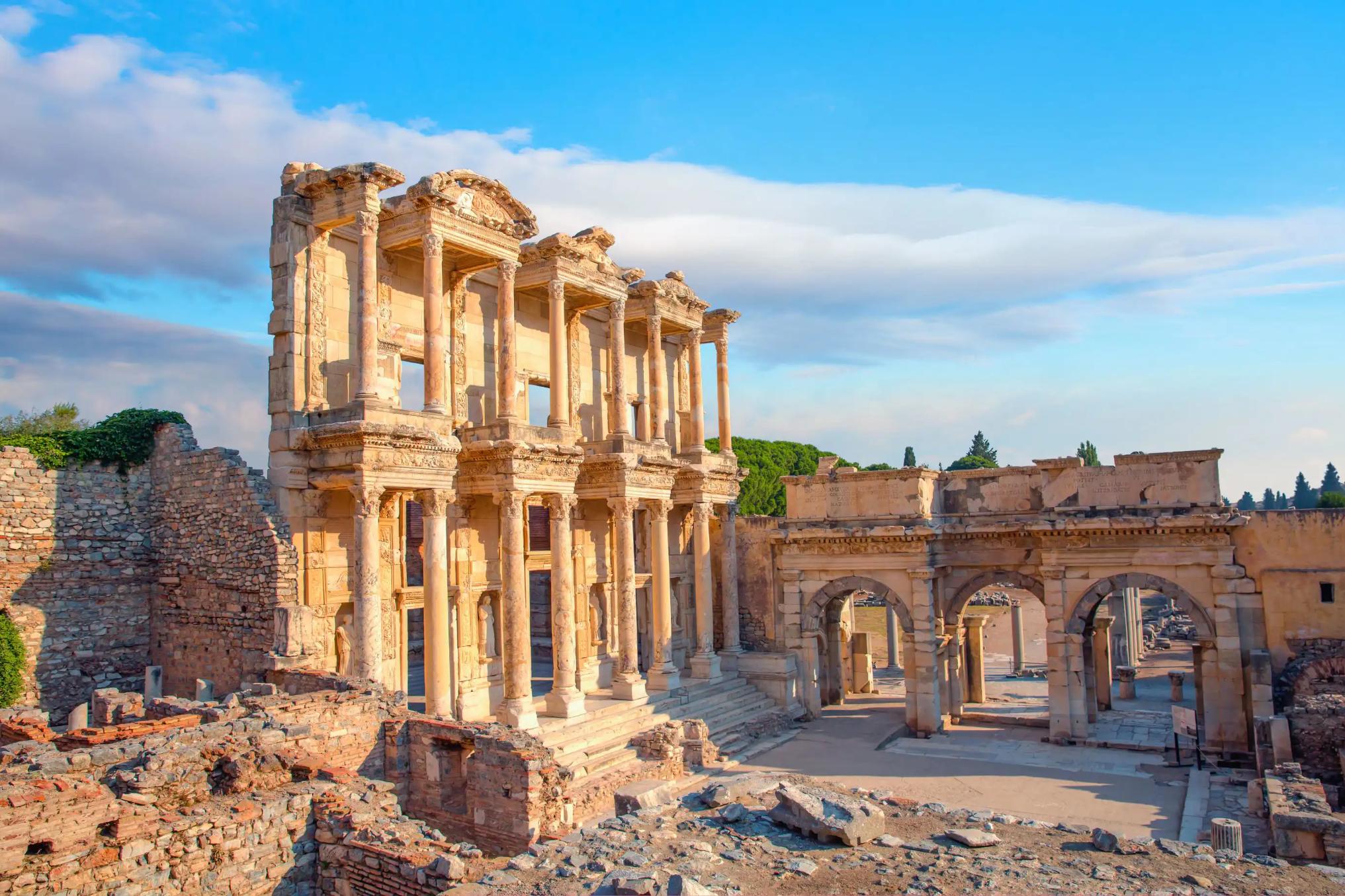 Ancient ruins of the Library of Celsus in Ephesus, Turkey, with a clear sky and warm sunlight highlighting the detailed stone architecture