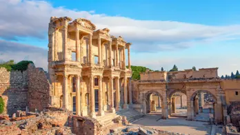 Ancient ruins of the Library of Celsus in Ephesus, Turkey, with a clear sky and warm sunlight highlighting the detailed stone architecture