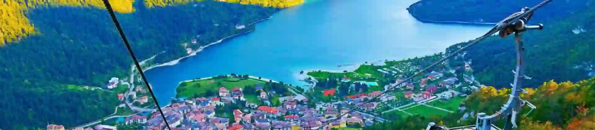 High angle view of the village of Molveno and Lake Molveno in Italy with a cable car in the forefront and the Dolomites in the background
