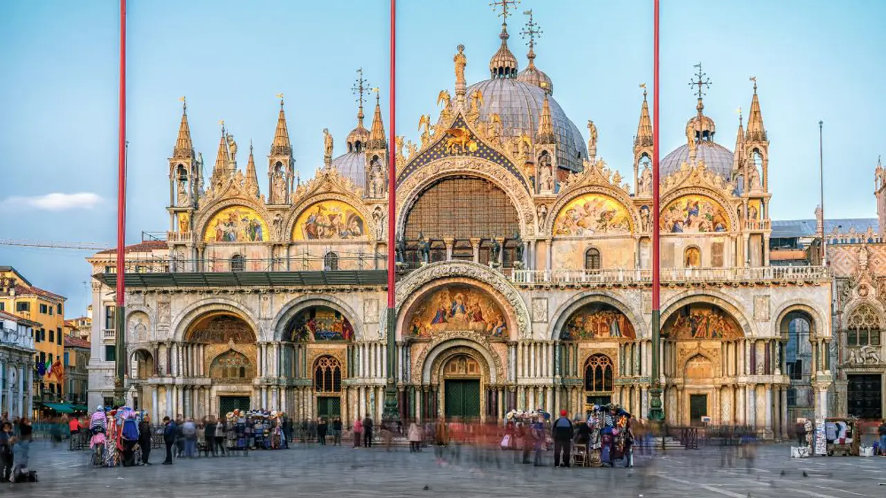 Exterior view of Saint Mark’s Basilica in Venice, Italy, showcasing its ornate façade with domes, arched windows, and detailed mosaics, reflecting Byzantine architectural style