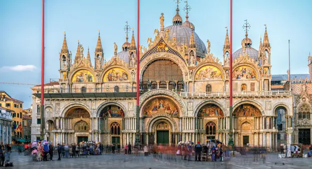 Exterior view of Saint Mark’s Basilica in Venice, Italy, showcasing its ornate façade with domes, arched windows, and detailed mosaics, reflecting Byzantine architectural style