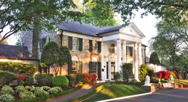 Graceland mansion in Memphis, Tennessee, the former home of Elvis Presley, featuring a grand white-columned façade surrounded by well-kept lawns and tall trees