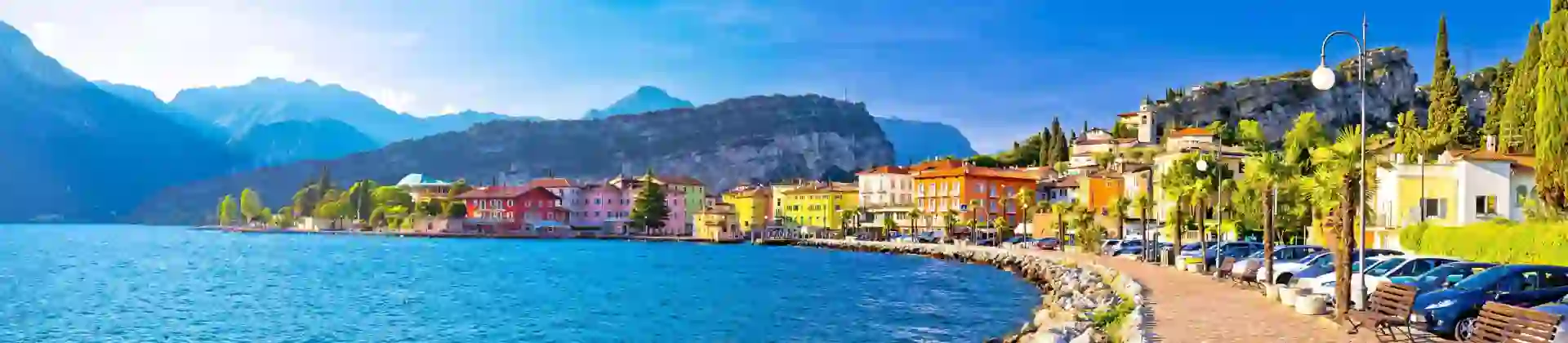 Waterfront in Torbole, Lake Garda, showing pavement and buildings and mountains in the distance