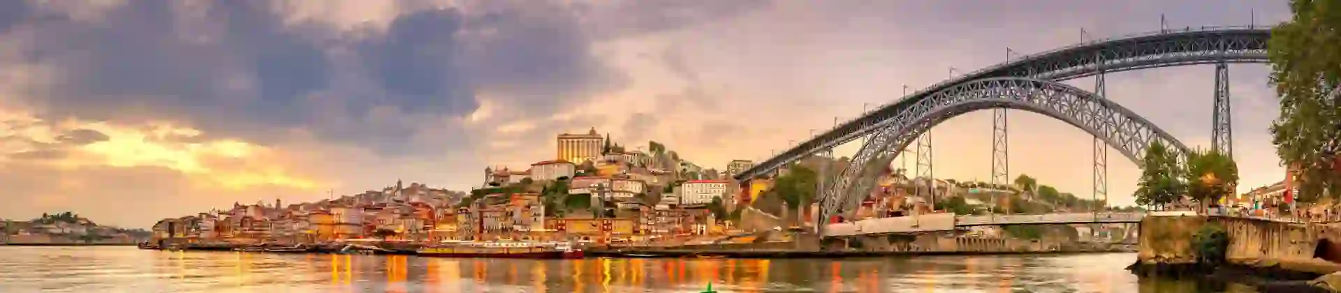 Picturesque view of Porto, Portugal, showing the Dom Luís I Bridge crossing the Douro River, with historic, colourful buildings along the riverbanks