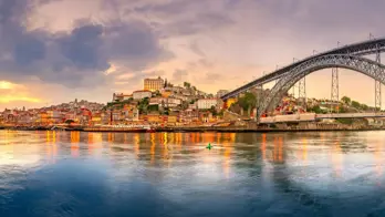 Picturesque view of Porto, Portugal, showing the Dom Luís I Bridge crossing the Douro River, with historic, colourful buildings along the riverbanks