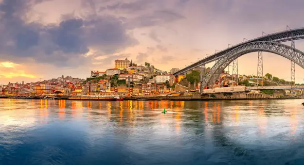 Picturesque view of Porto, Portugal, showing the Dom Luís I Bridge crossing the Douro River, with historic, colourful buildings along the riverbanks