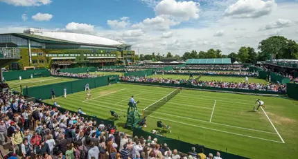 Crowds watching tennis matches on the grass courts at Wimbledon under a blue sky