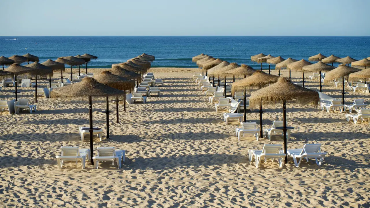 Beach at Praia de Monte Gordo on the Algarve with sunbeds and parasols on the sand, and the sea visible in the distance
