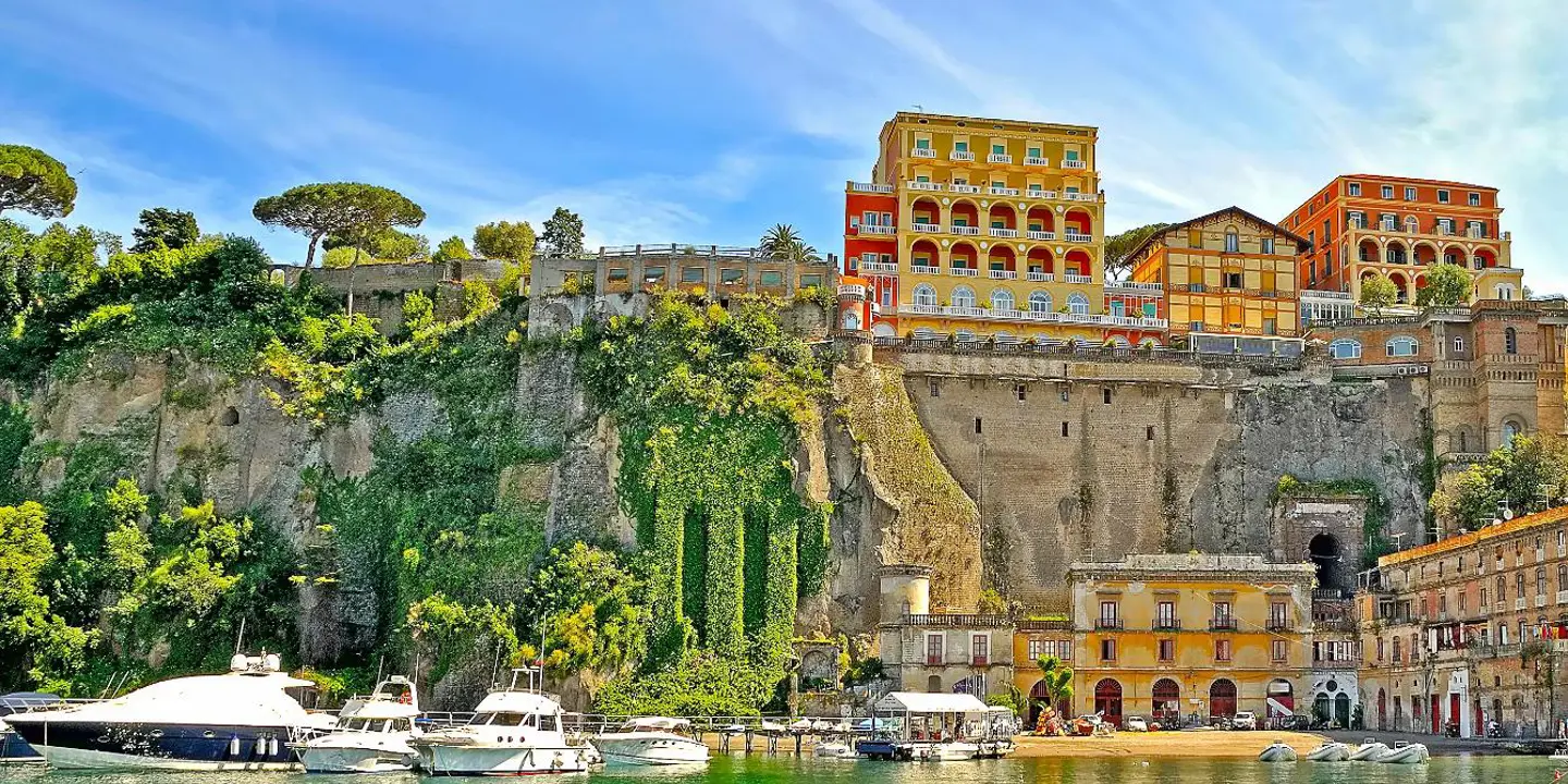 View of Sorrento from the water, with boats in the forefront and hotels and restaurants on the cliff top