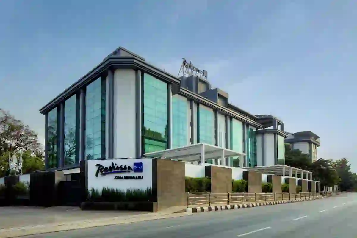 Exterior view of the Radisson Blu Atria hotel in Bengaluru, showcasing a contemporary design with tall glass façades and a stylish entrance
