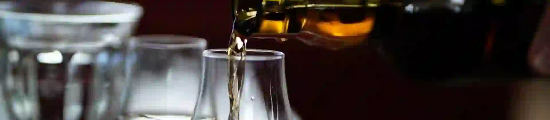 Close up of a glass of Scottish whisky being poured with dark lighting