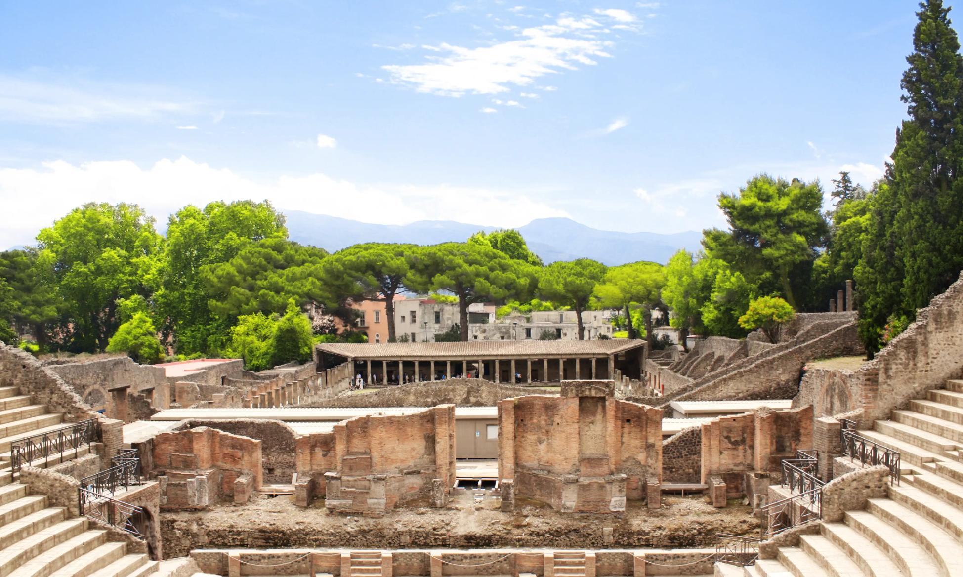 The theatre district in Pompeii with the ancient theatre in the foreground and the Quadriporticus - a large rectangular courtyard surrounded by covered walkways visible behind it