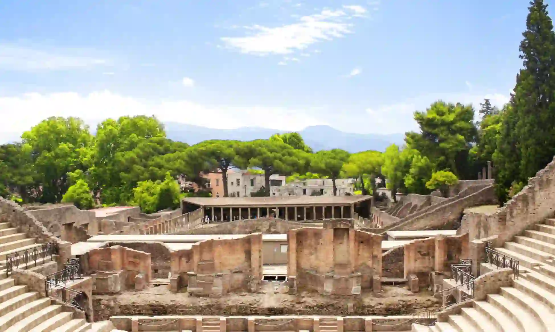 The theatre district in Pompeii with the ancient theatre in the foreground and the Quadriporticus - a large rectangular courtyard surrounded by covered walkways visible behind it