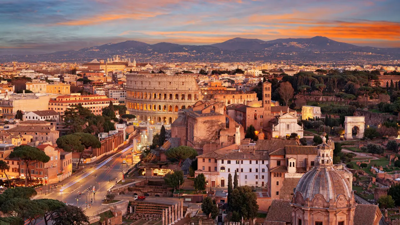 Cityscape of Rome at sunset, showing the Colosseum and St. Peter's Basilica 