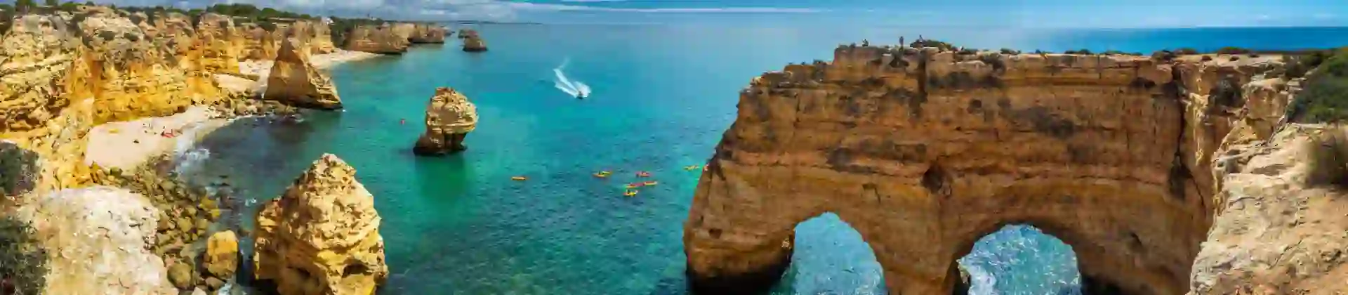 Scenic view of the coves, natural rock arches, and turquoise sea at Praia da Marinha on the Algarve, with rugged cliffs and clear water