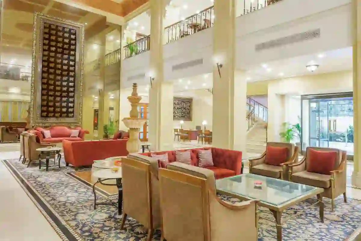 Radisson Hotel in Varanasi's elegant lobby with plush red and beige seating, ornate décor and a patterned rug beneath warm lighting