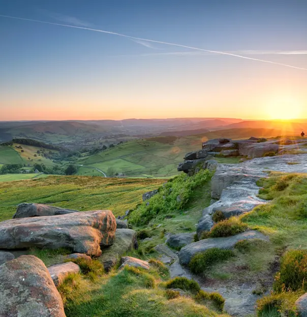 View of the Peak District at sunrise, with the sun creeping over the mountains