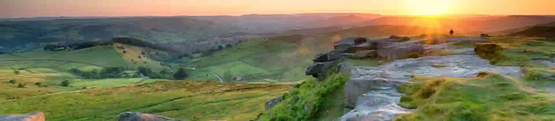 View of the Peak District at sunrise, with the sun creeping over the mountains