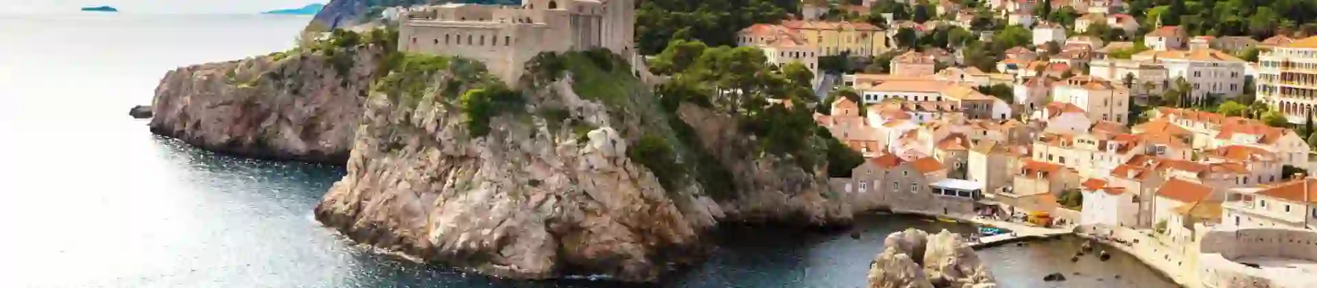 Panoramic view of the walled Old Town of Dubrovnik, Croatia, perched on a rocky coastline beside the blue waters of the Adriatic Sea