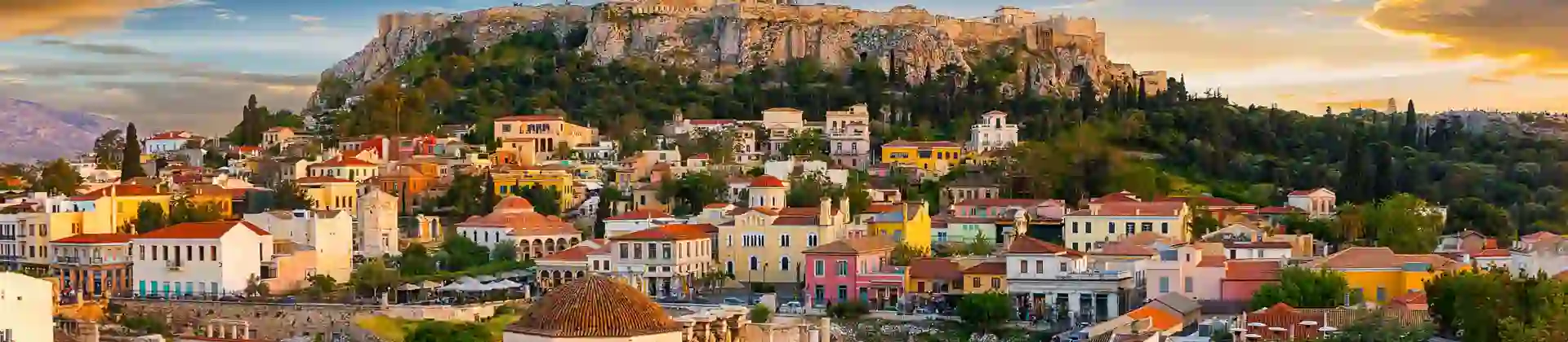 View of a city with colourful buildings and a rocky hill with ruins on the top.